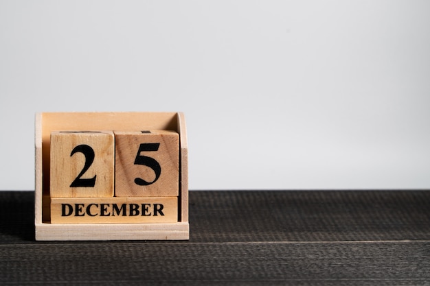 Calendrier de bloc en bois sur la date de Noël 25 décembre sur un fond en bois noir.