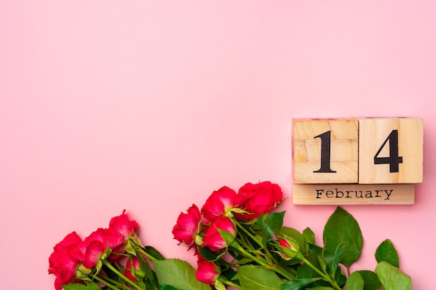Photo calendrier en bois 14 février et roses sur fond rose à plat