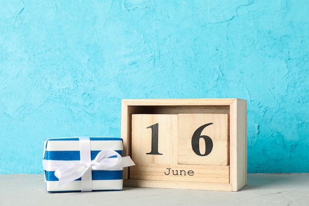 Calendrier en bois cubes date du 16 juin et coffret cadeau sur tableau blanc sur fond de couleur, espace pour le texte