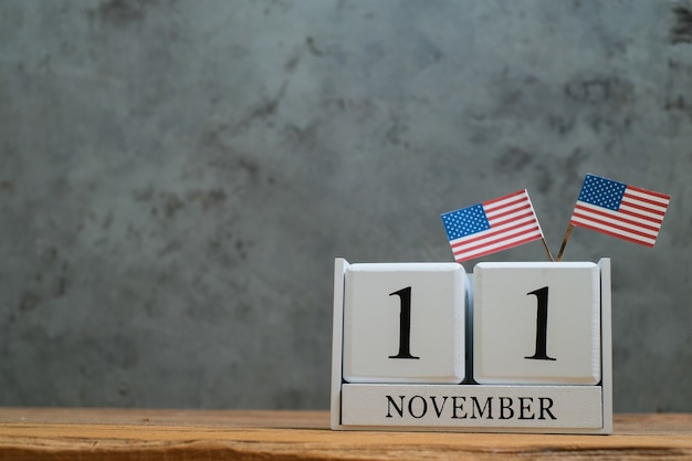 Photo calendrier en bois du 11 novembre avec des drapeaux américains miniatures. concepts de célébration de la journée mondiale des anciens combattants