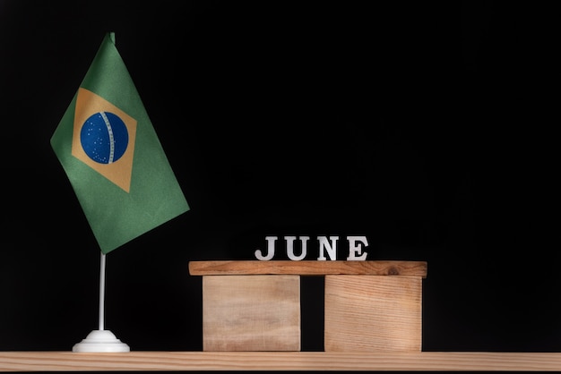 Calendrier en bois de juin avec drapeau brésilien sur fond noir. Dates du Brésil en juin.