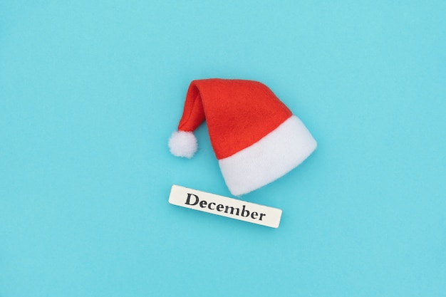 Calendrier en bois mois d'hiver décembre et bonnet de noel sur papier bleu