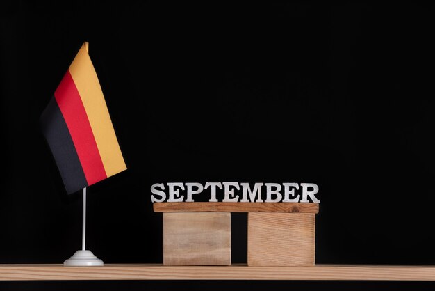 Calendrier en bois de septembre avec drapeau allemand sur fond noir. Dates en Allemagne en septembre.
