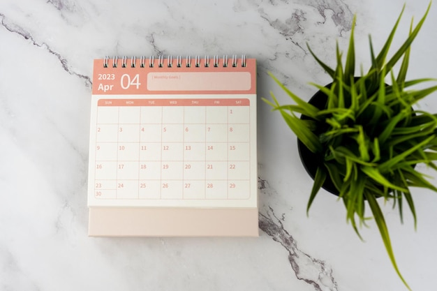 Photo calendrier de bureau d'avril 2023 sur une table en marbre à plat avec une plante en pot