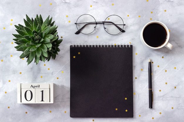 Calendrier de bureau ou de table à domicile le 1er avril. bloc-notes, café, succulent, lunettes sur fond de marbre