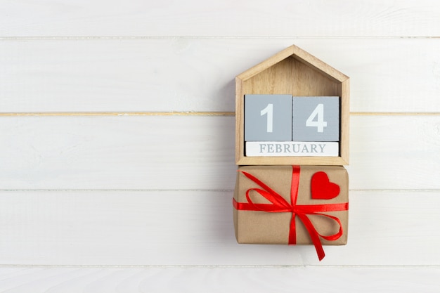 Calendrier de cube avec coeur rouge et boîte-cadeau sur une table en bois avec fond. 14 février