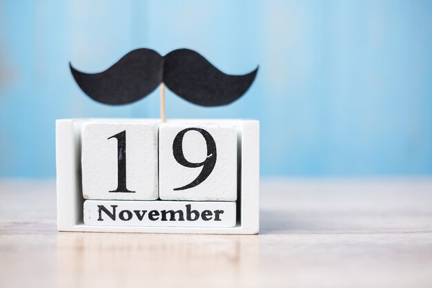 Calendrier du 19 novembre et moustache sur une table en bois. Père, Journée internationale des hommes, Sensibilisation au cancer de la prostate