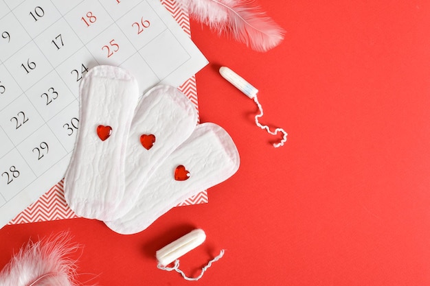 Calendrier du cycle menstruel féminin avec tampons et tampons sur fond rouge