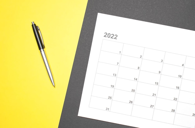 Photo calendrier du mois calendaire pour prendre rendez-vous ou gérer le calendrier chaque jour et stylo sur fond jaune pour planifier le travail et le concept de voyage.