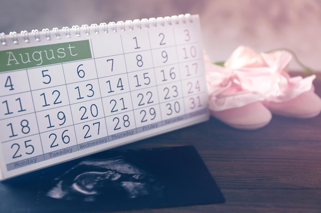 Calendrier avec échographie de chaussures pour bébés et enfants sur table en bois