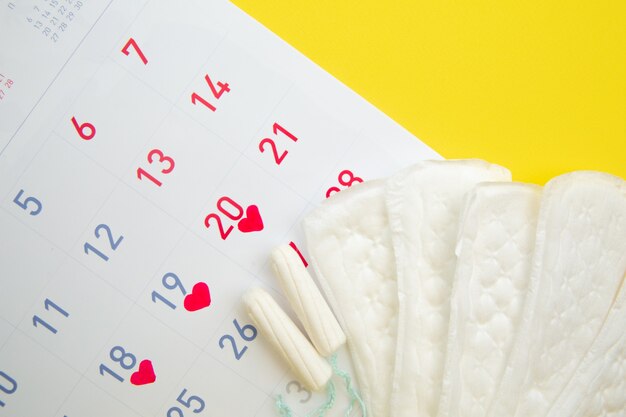 Calendrier Menstruel Avec Des Tampons En Coton Et Des Serviettes Hygiéniques Sur Jaune