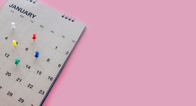 Calendrier et planificateur de rendez-vous avec une épingle sur fond rose.