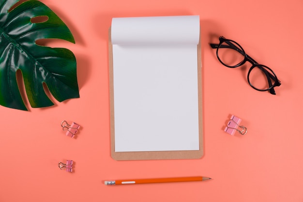 Calendrier plat à poser avec presse-papiers, feuilles de palmier et crayon sur corail vivant