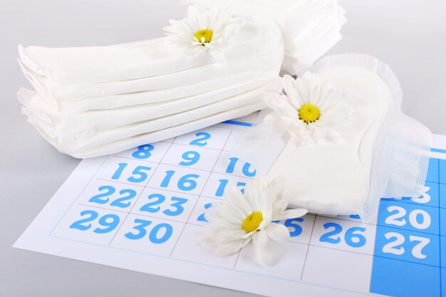 Calendrier des serviettes hygiéniques et fleurs blanches sur fond clair