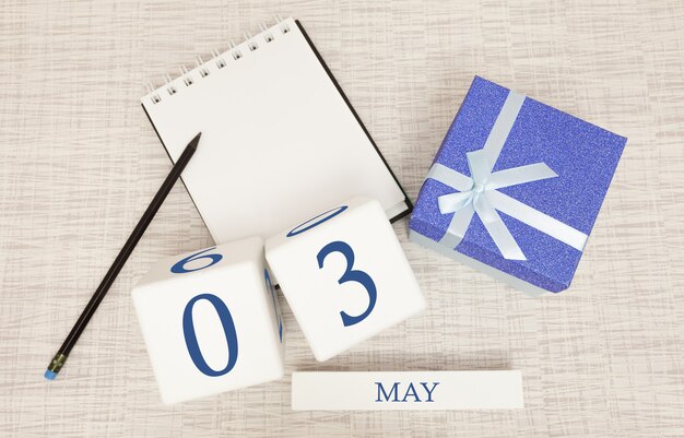 Calendrier avec texte et chiffres bleu tendance pour le 3 mai et un cadeau dans une boîte.