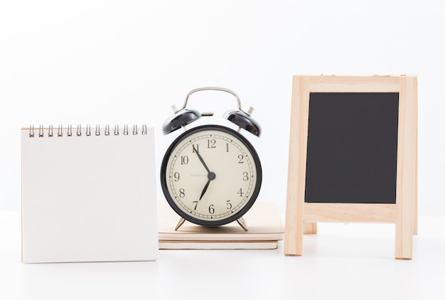 Calendrier vierge et tableau noir et heure de l'horloge à cinq minutes à sept heures sur blanc