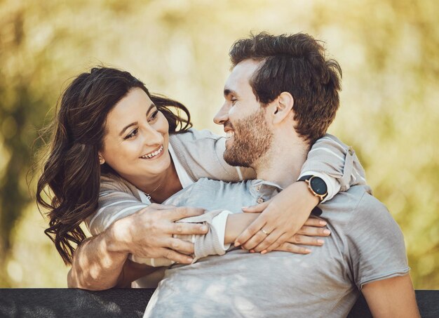 Câlin amour et couple sur un banc de parc sourire et s'amuser ensemble à l'extérieur Romance de la Saint-Valentin se détendre et prendre soin d'un homme et d'une femme heureux étreignant et câlinant à un rendez-vous romantique à l'extérieur