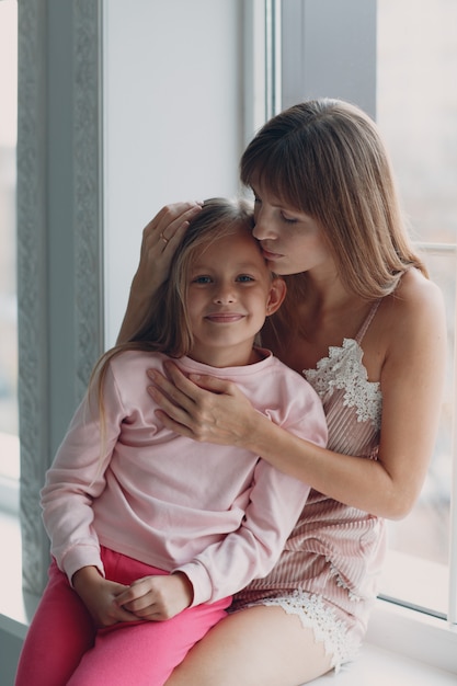 Câlin de mère avec une petite fille. Rester à la maison.