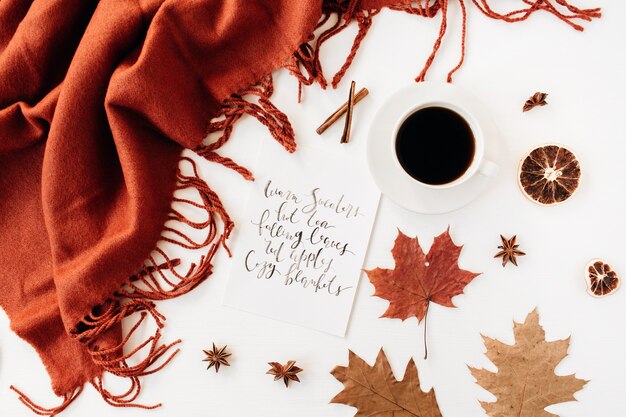 Calligraphie de composition automne automne avec tasse de café, couverture de gingembre, feuilles séchées, étoile de cannelle, anis et orange sur le tableau blanc