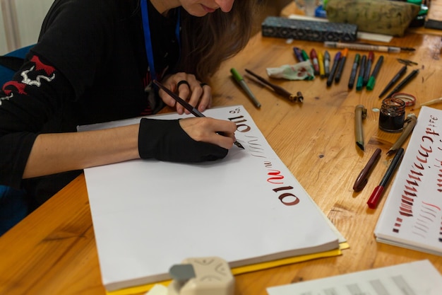 Une calligraphiste expérimentée s'entraîne à écrire et à dessiner des polices de style renaissance dans un carnet de croquis