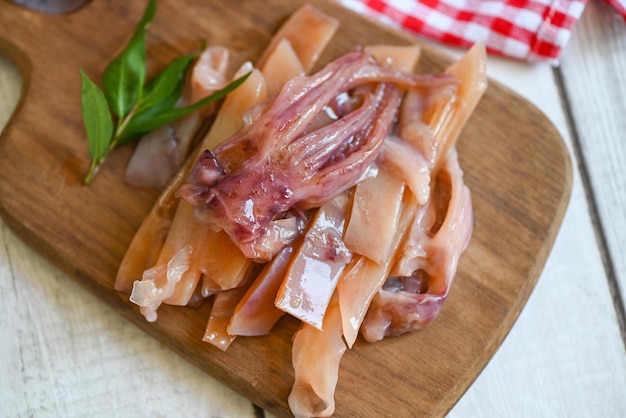 calmar cru pour la cuisson des aliments sur une planche à découper en bois, calmar mariné sur assiette, conservation des fruits de mer - vue de dessus