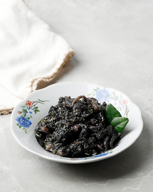 Calmars sautés et piment en sauce noire ou Cumi Hitam servis dans une assiette en céramique
