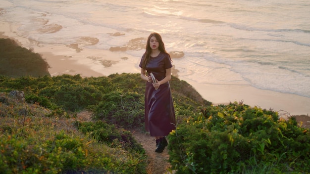 Calme brune détente bord de mer debout colline tenant livre fille posant nature