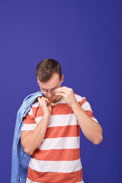 Calme gentil homme tient une chemise en jean avec sa main