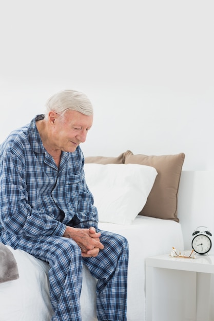 Calme homme âgé assis sur le lit