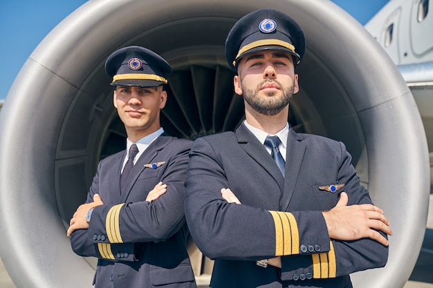 Photo calmer les jeunes hommes en uniforme debout devant le turboréacteur