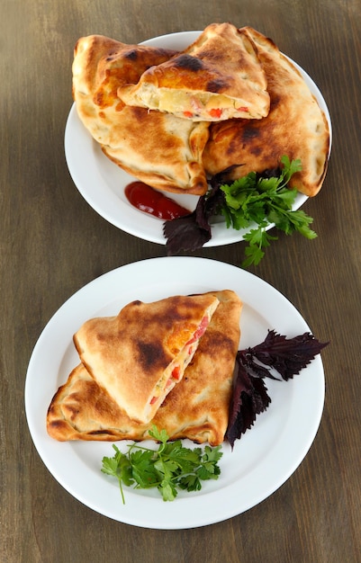 Calzones à pizza sur des assiettes sur une table en bois