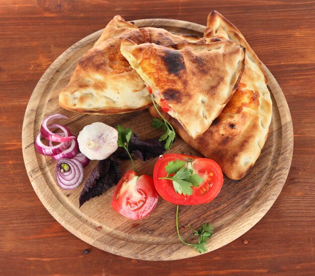 Des calzones de pizza sur une planche en bois sur une table en bois