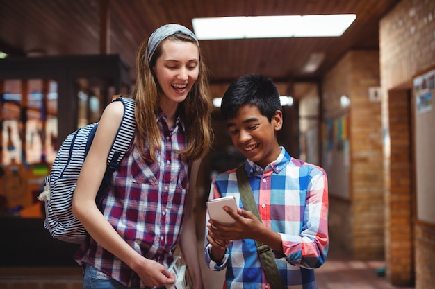 Camarades de classe à l'aide de téléphone portable dans le couloir de l'école