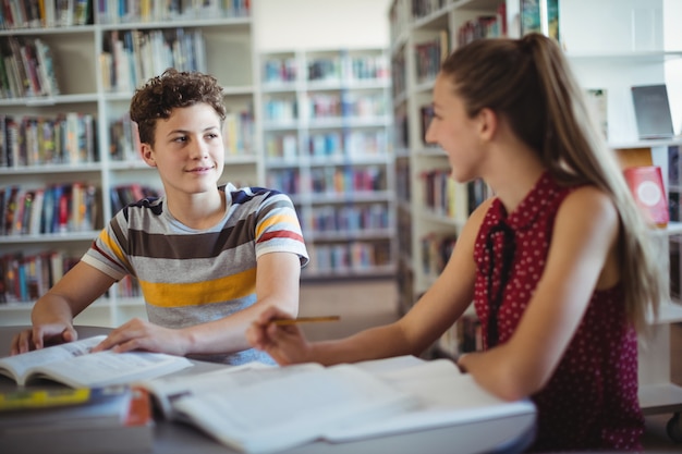 Les camarades de classe interagissent tout en faisant leurs devoirs dans la bibliothèque