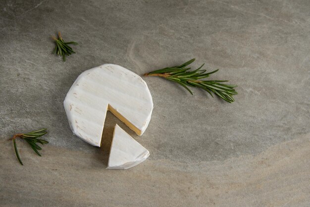 Photo camembert au fromage ou brie au romarin sur une planche à découper sur fond de pierre de marbre. espace de copie. photographie d'atelier. vue de dessus.