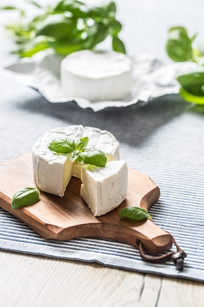 Camembert ou brie avec feuilles de basilic sur table.