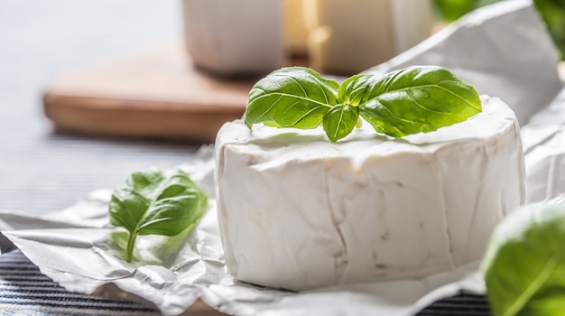 Camembert ou brie avec feuilles de basilic sur table.