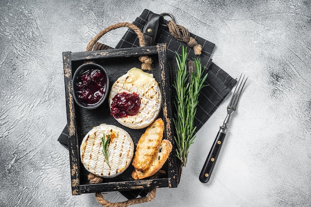 Camembert Brie grillé avec un toast de sauce aux canneberges et romarin dans un plateau en bois Fond blanc Vue de dessus