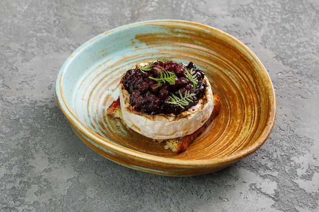 Camembert cuit au four avec des pignons de pin et des herbes sur le dessus