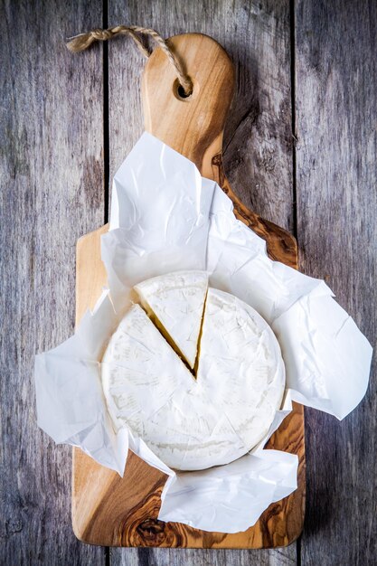 Camembert entier et portion sur une planche à découper d'olive