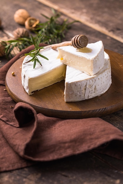 Camembert de ferme biologique ou fromage brie sur planche de bois avec romarin et noix, miel.