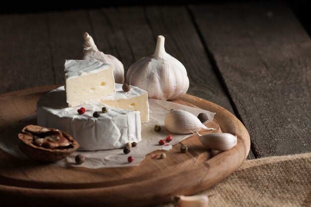 Camembert et fromage brie sur bois avec tomates, laitue et ail. Nourriture italienne. Les produits laitiers.