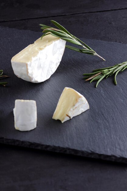 Camembert et romarin sur planche d'ardoise fromage doux avec moisissure blanche sur fond sombre