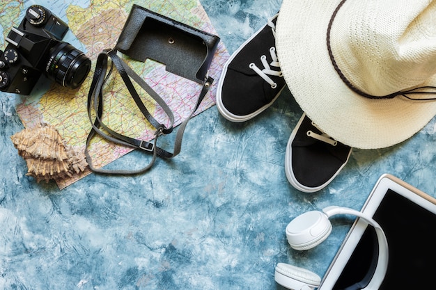 Caméra d&#39;accessoires de voyage, chapeau de paille, carte, chaussures sur une disposition de vue de dessus plat fond bleu avec espace de copie