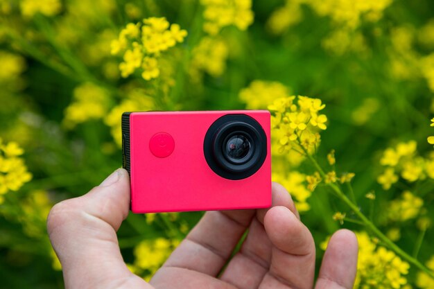 Caméra d'action dans les mains sur un fond vert avec des fleurs