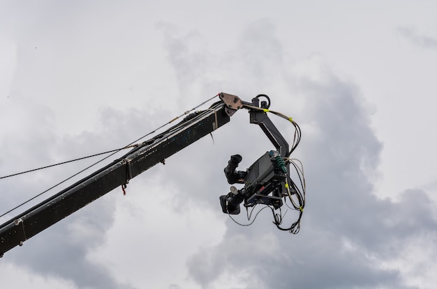 Caméra de cinéma et de télévision suspendue à une grue de diffusion avec le ciel nuageux en arrière-plan.