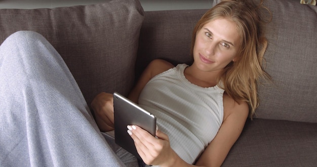 La Caméra Commence Avec Une Jolie Fille Sur Le Canapé En Train De Lire Quelque Chose Sur Sa Tablette Et Se Dirige Vers Un Sol Gris Industriel