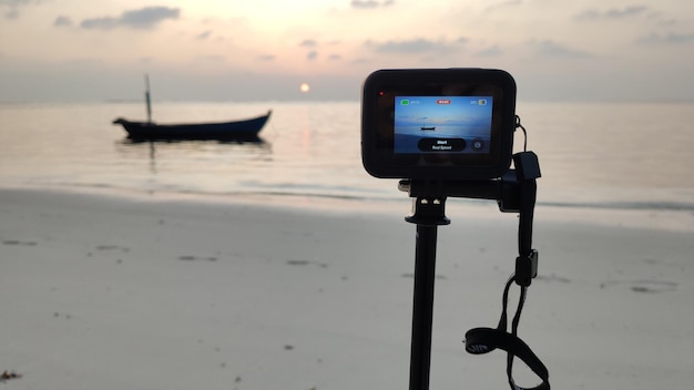 Une caméra vidéo sur un trépied capture un magnifique coucher de soleil sur la plage