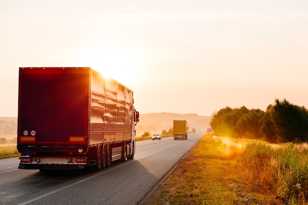 Camion arrivant sur la route dans un paysage rural au coucher du soleil