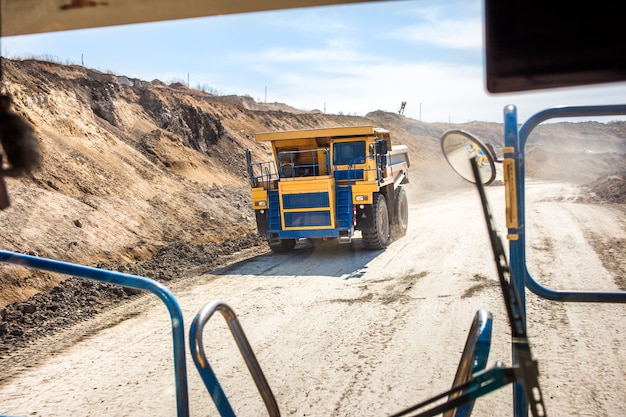 Camion à benne basculante jaune se déplaçant dans une mine de charbon. Vue d'un autre camion